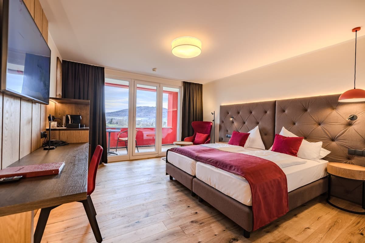Une chambre d’hôtel équipée d’un lit, d’un bureau, d’une télévision et offrant une vue sur l’extérieur.