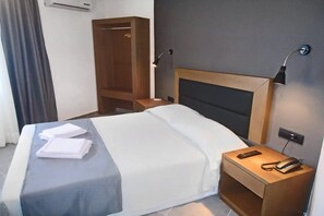 A hotel room with a bed, bedside tables, a wardrobe, and a wall-mounted phone. - Evita Blue Hotel (Xylokastro-Evrostina)