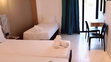 Quarto de hotel com duas camas, uma escrivaninha e uma cadeira.