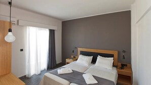 Habitación de hotel con una cama grande, mesitas de noche, un escritorio y una ventana con cortinas.