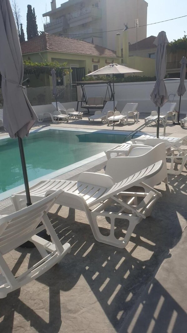 Un espace aménagé au bord de la piscine, avec des chaises longues et des parasols.