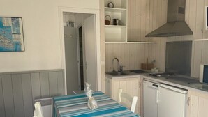 A compact kitchen with a striped tablecloth, a sink, and a stove. - Cottage Les Roses de mer (Sainte-Marie-de-Ré)