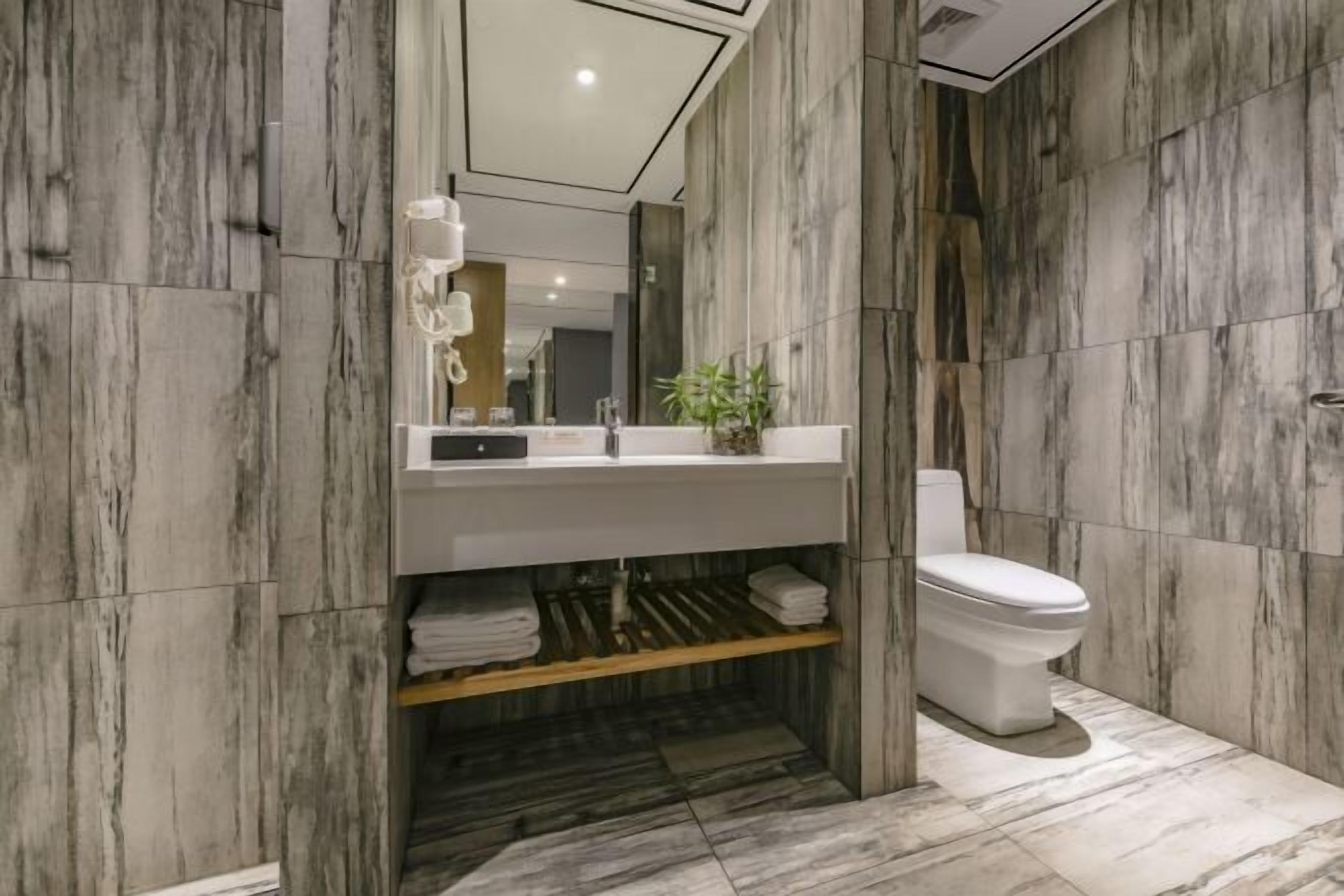 A modern bathroom with a marble wall design, a white sink, and a toilet.