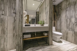 Un baño moderno con diseño de pared de mármol, un lavamanos blanco y un inodoro.
