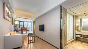 Une chambre d’hôtel moderne, dotée d’un canapé, d’une petite table, d’une télévision et d’une salle de bain au sol en marbre.