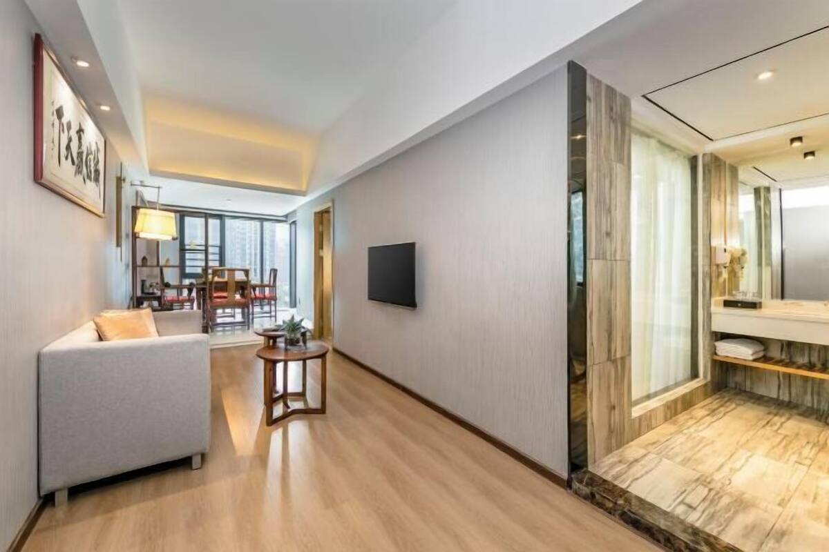 Habitació d'hotel moderna amb sofà, taula petita, televisió i bany amb terra de marbre.