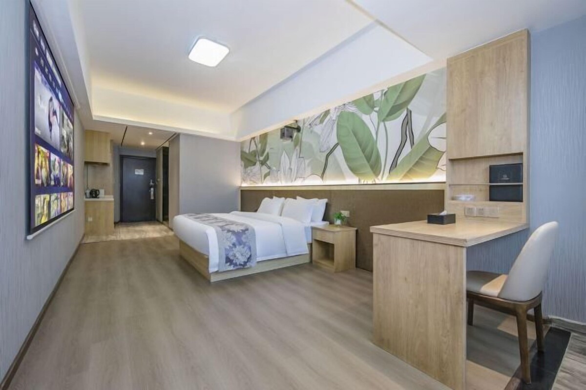 Una habitación de hotel moderna con cama, escritorio y un panel decorado con motivos de hojas.