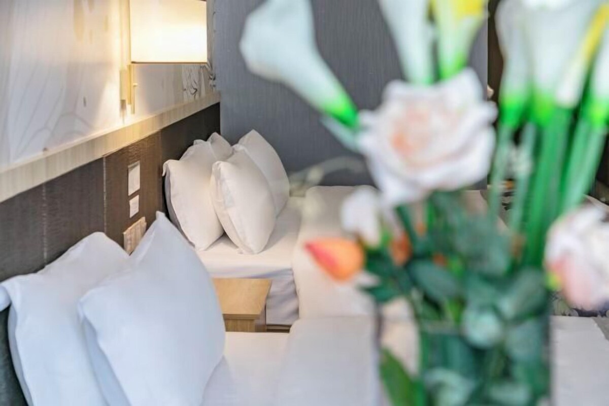 Una habitación de hotel con cama, almohadas y una mesita de noche.