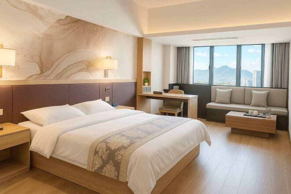 Habitació d'hotel amb un llit gran, un escriptori, un sofà i vistes a la ciutat.