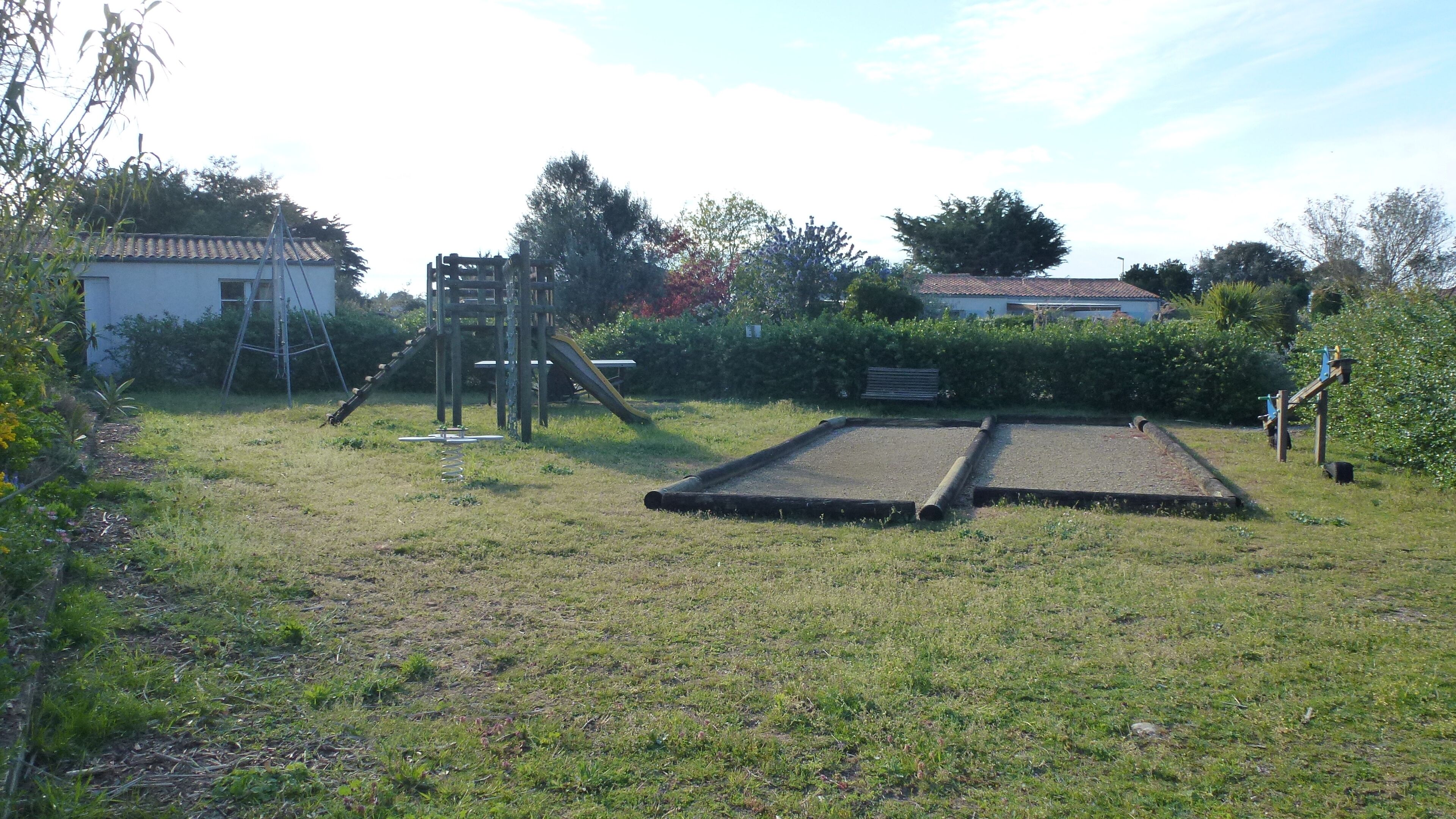A grassy outdoor area with a trampoline, a climbing structure, and a small shed.