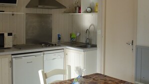 A kitchen with wooden cabinets, a built-in oven, a sink, and a dining table with chairs.