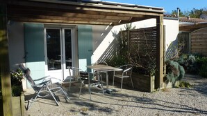 A patio with a table and chairs, a sliding glass door, and a wooden fence.