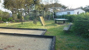 A playground with a slide, swings, and a table.