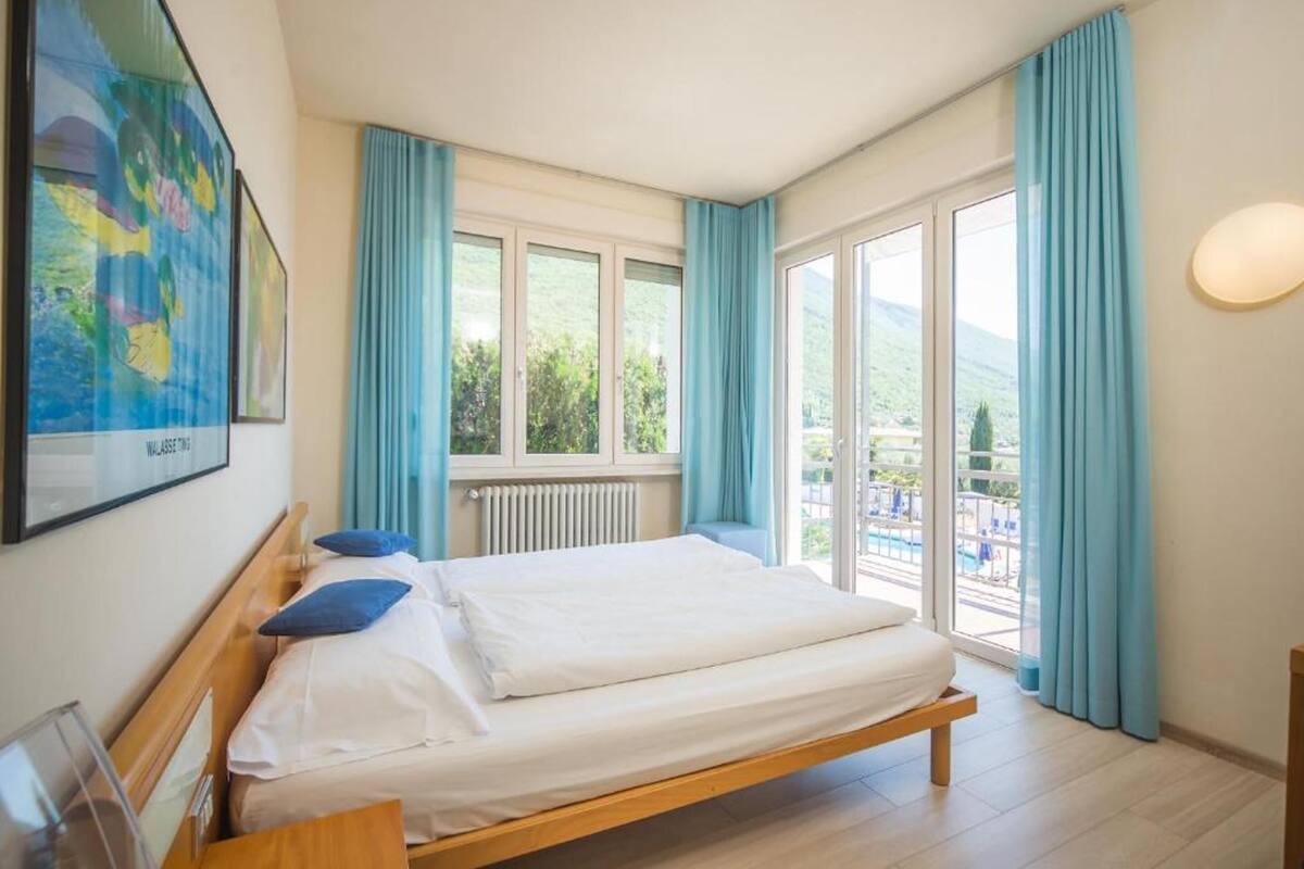 Una habitación de hotel con cama, ventana y vista a una piscina.