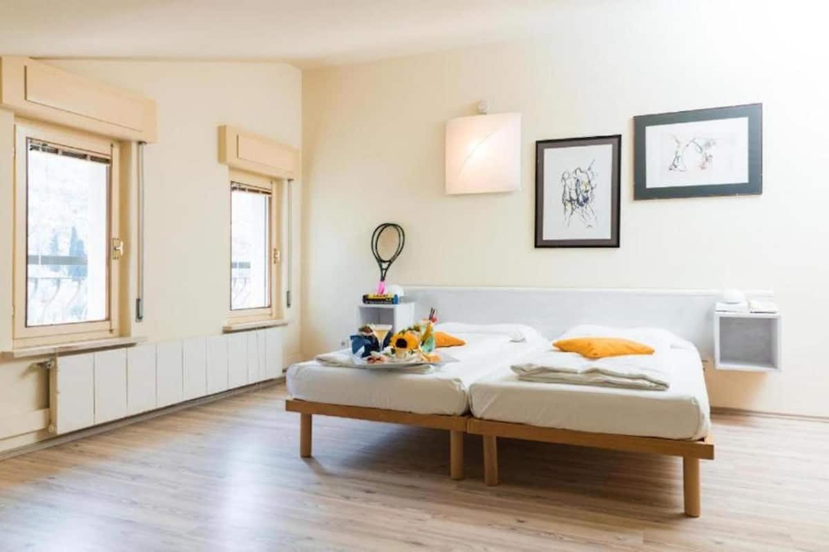 Habitación de hotel con dos camas, un ventanal grande y obras de arte en la pared.