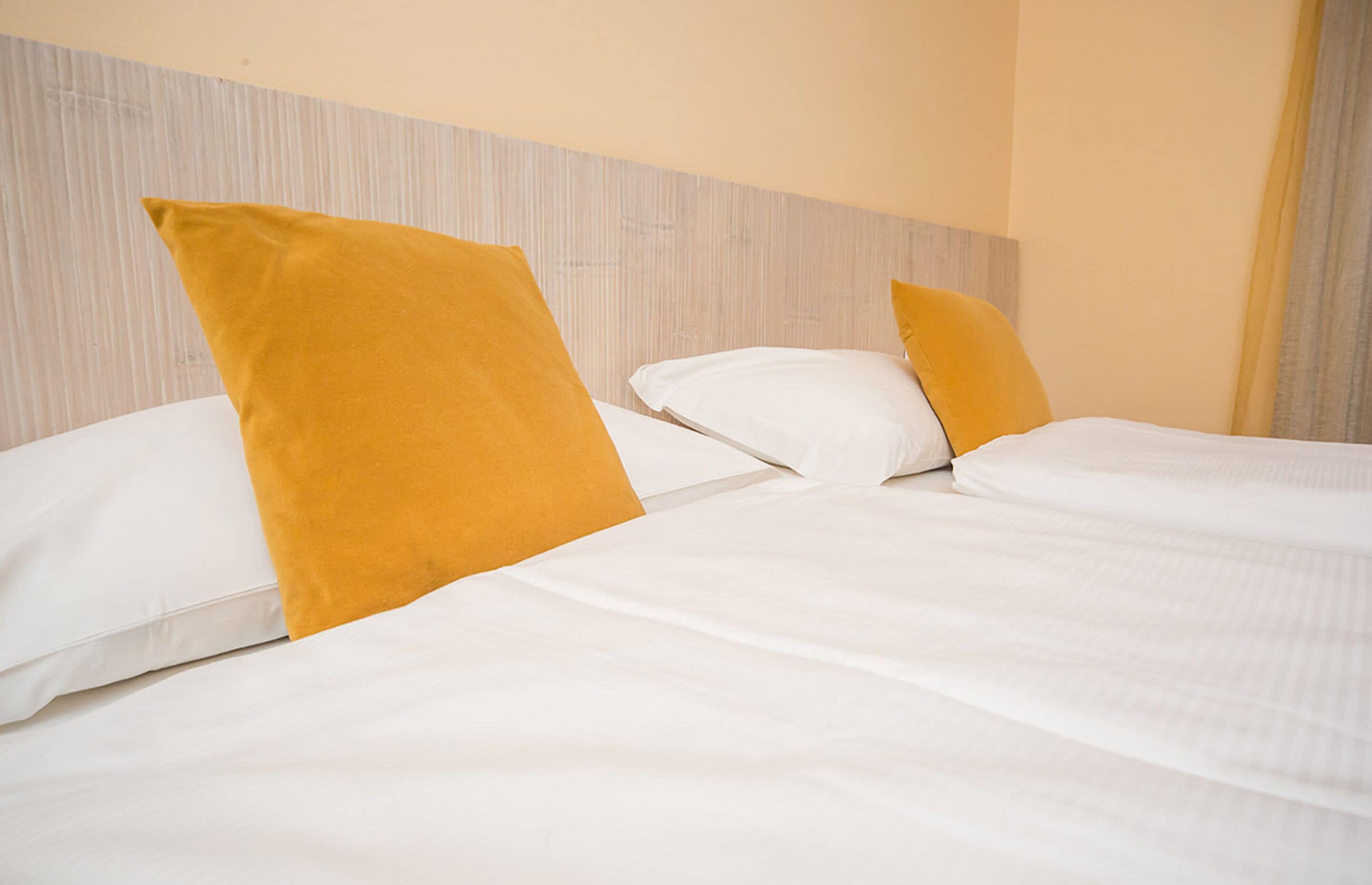 A hotel room with two beds, each with white linens and a wooden headboard.