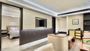 A modern hotel room with a bed, a seating area, a desk, and a large mirror.