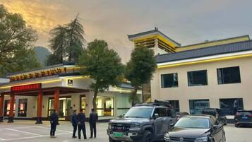 A parking lot with several vehicles, a building with a sign, and a group of people standing.