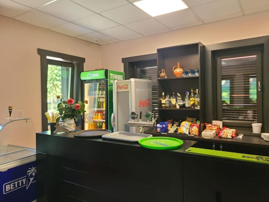 Een barruimte met een koelkast, planken vol snacks en een raam met jaloezieën.