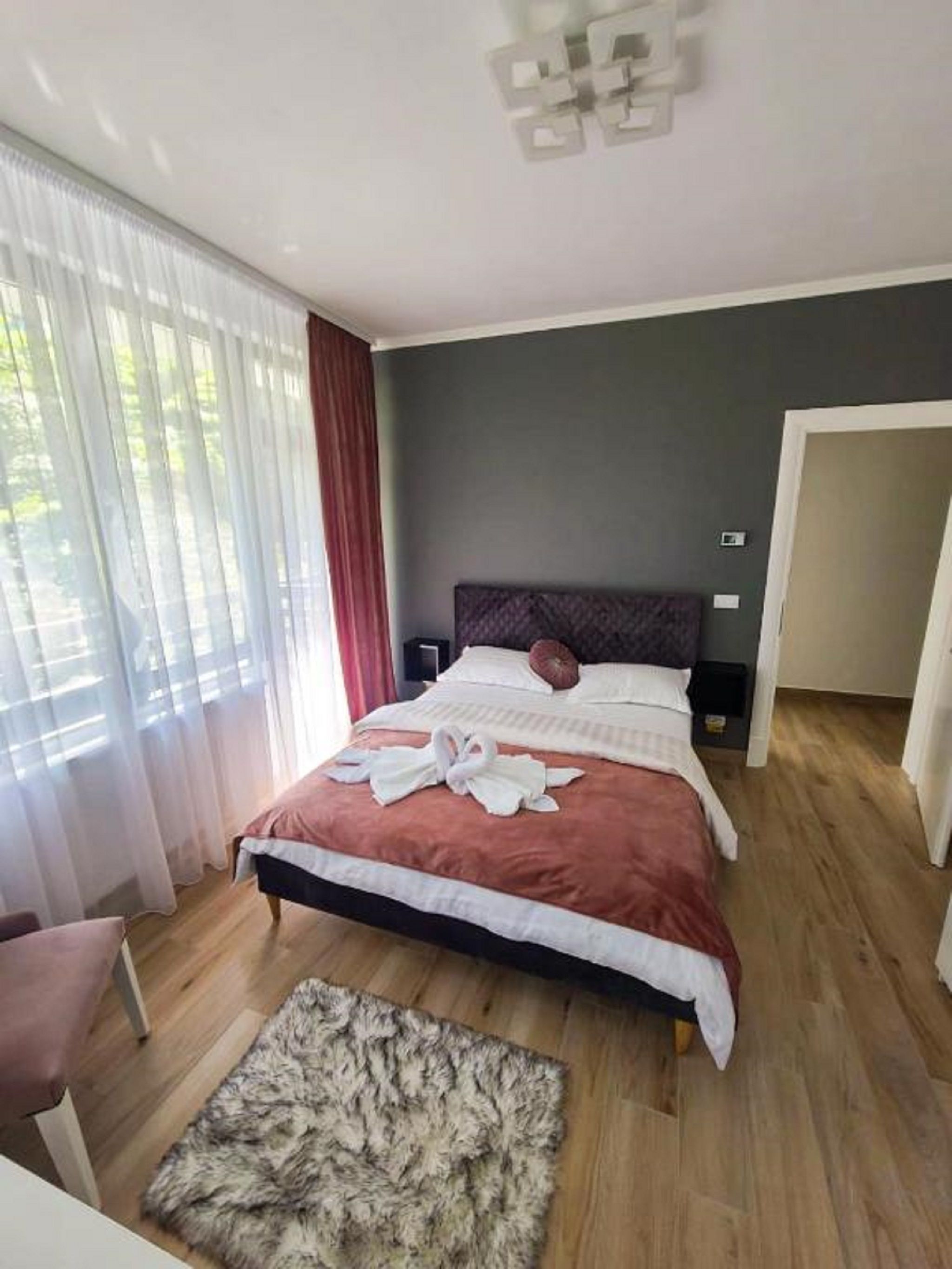 Een slaapkamer met een bed, nachtkastje, stoel en vloerkleed.