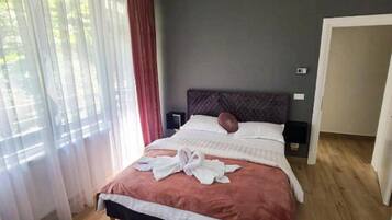 Een slaapkamer met een bed, nachtkastje, stoel en vloerkleed.