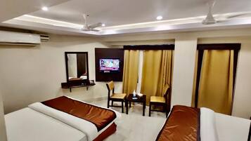 A hotel room with two beds, a TV, a desk, and a chair.