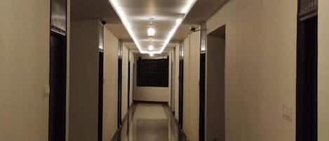 Un pasillo largo y estrecho con suelo reflectante y una serie de puertas a ambos lados.