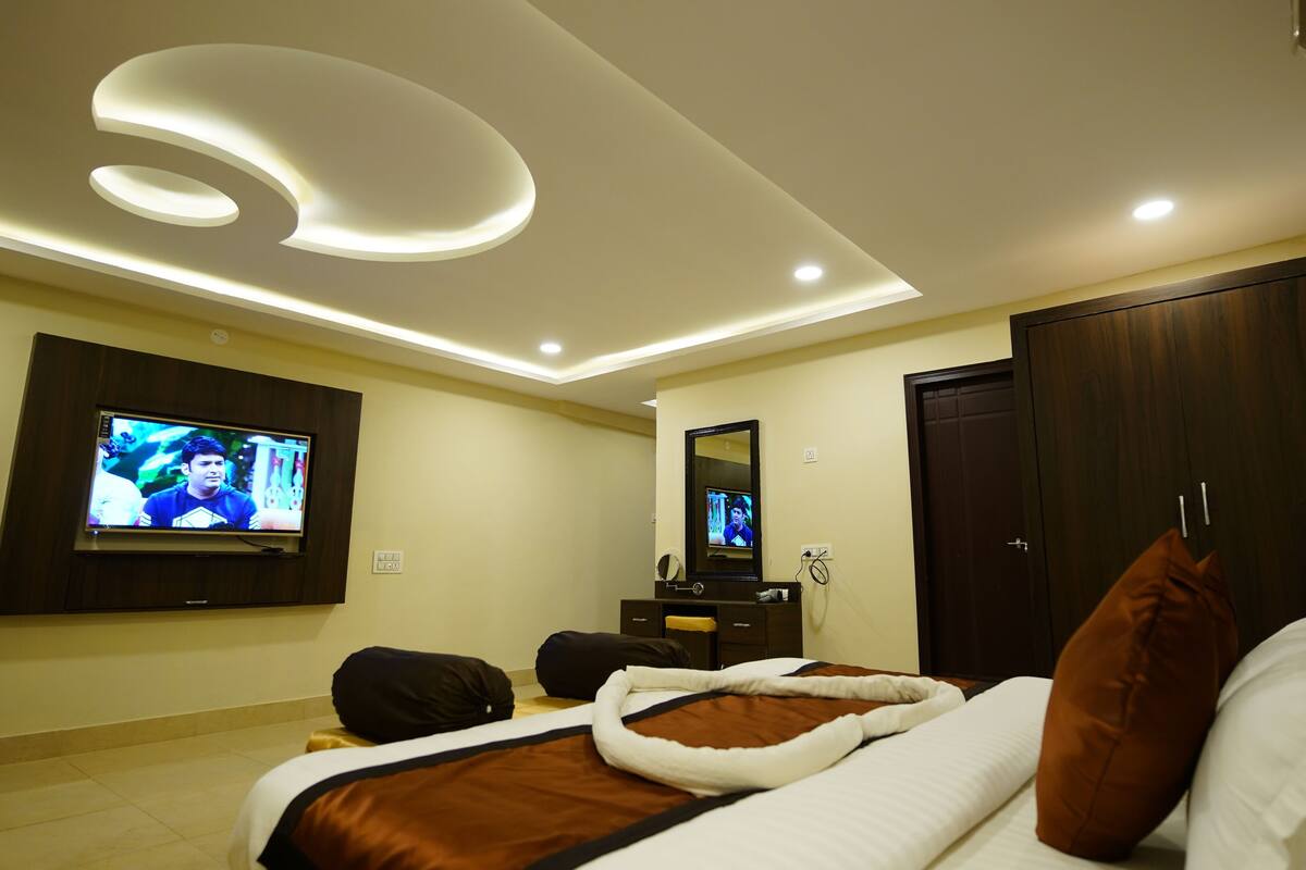 Un dormitorio moderno con cama, televisión, armario e iluminación empotrada en el techo.