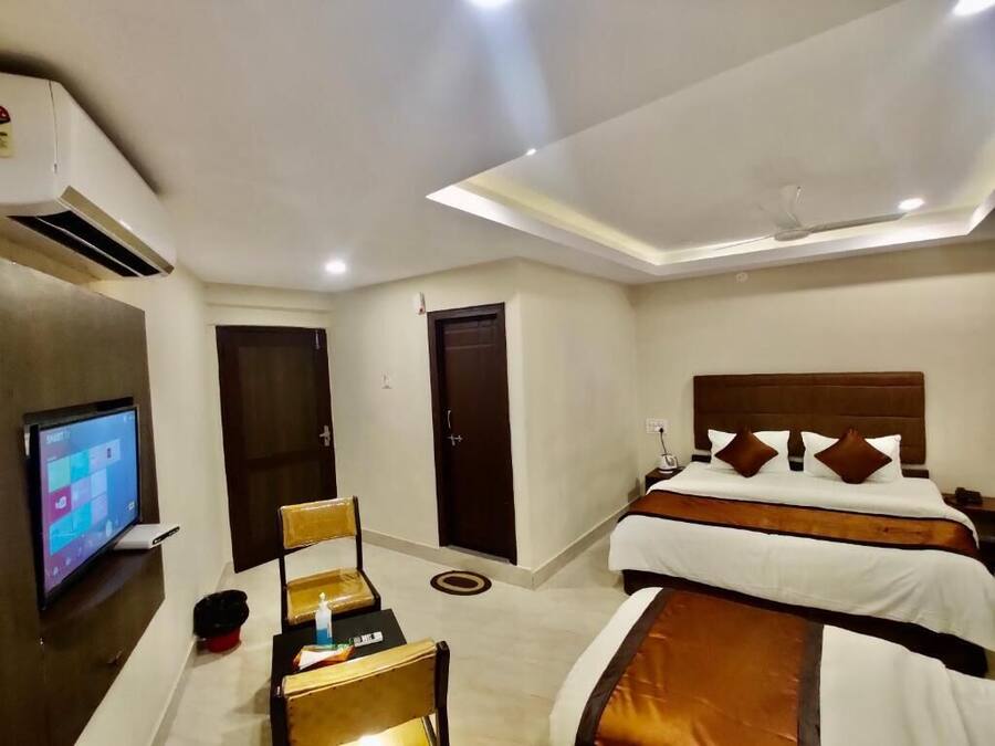 A hotel room with a bed, bedside table, TV, and a desk with a chair.