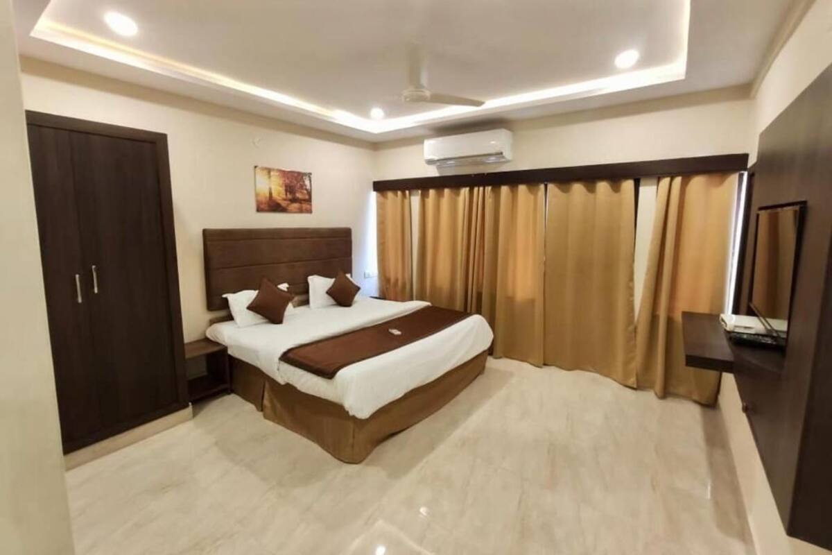 Un dormitorio moderno con una cama grande, un armario, un equipo de aire acondicionado y un televisor.