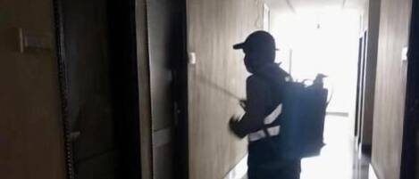 A person walking down a dimly lit hallway with doors on either side.