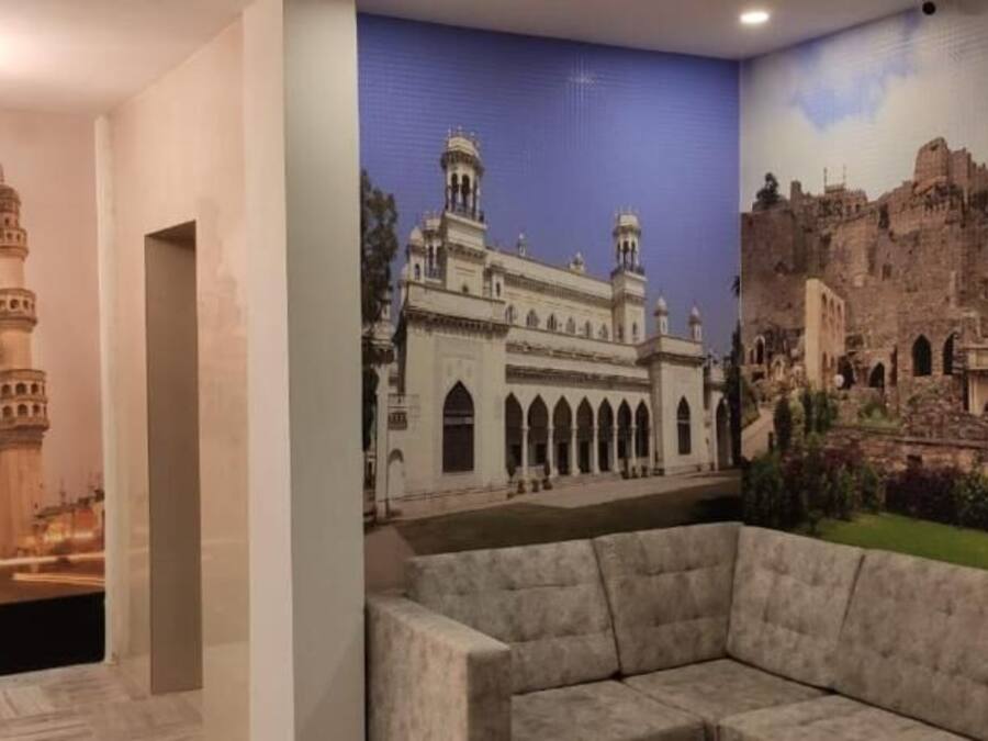 A room with a large mural of a historical building, a chandelier, and a sofa.