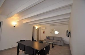 Una sala de estar moderna con comedor, que incluye un sofá, una mesa de centro y una mesa de comedor con sillas.