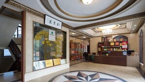 A lobby with a central circular mosaic floor, a reception desk, and a bookshelf filled with books. - Hongyezhai Ecological Leisure Villa (Hengyang)