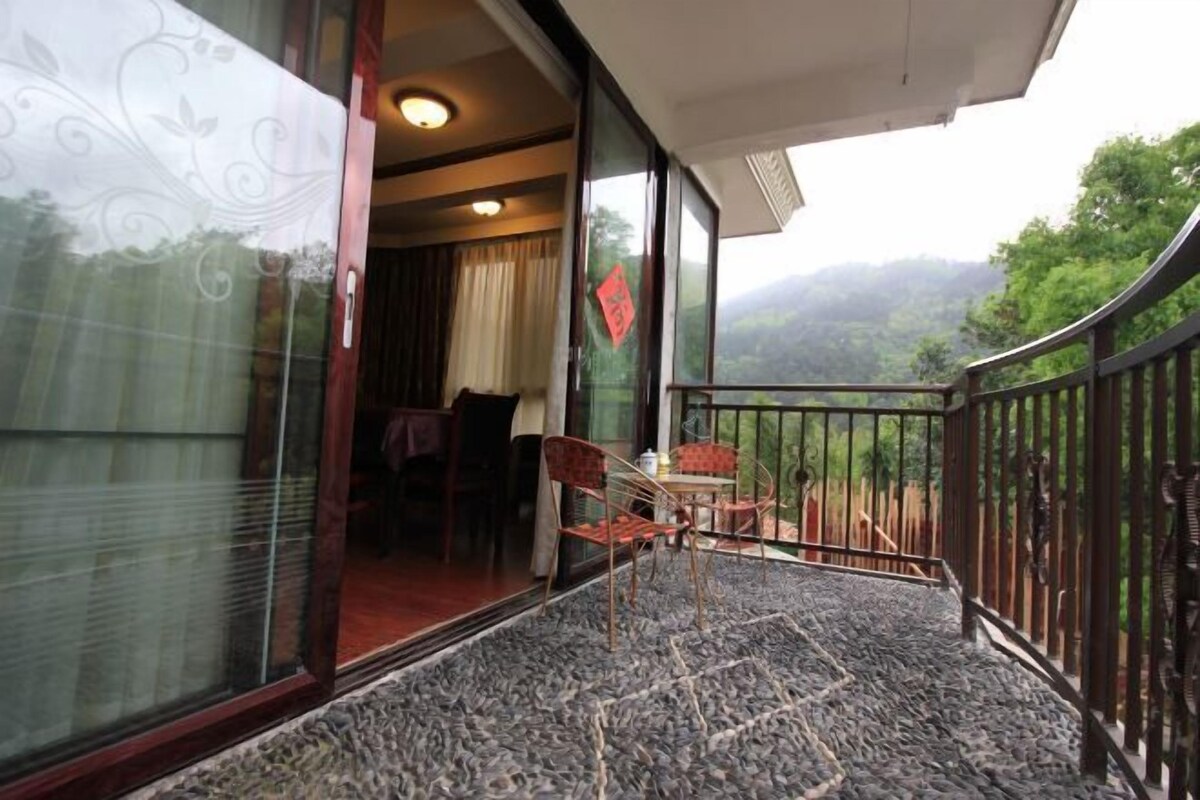 A balcony with a table and chairs, a view of the outdoors, and a red decoration on the wall.