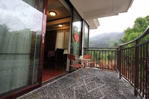 A balcony with a table and chairs, a view of the outdoors, and a red decoration on the wall. - Hongyezhai Ecological Leisure Villa (Hengyang)
