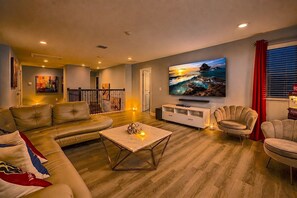 Ein Wohnzimmer mit einer Ledersofa, einem Couchtisch, einem an der Wand befestigten Fernseher und einem roten Vorhang.