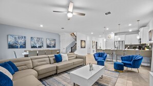 A modern living room with a beige sectional sofa, a white coffee table, and blue accent chairs. - Professionally Purpose Built Vacation Oasis- New Discounts Just Applied! (Davenport)