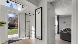 Un interior moderno con un amplio ventanal corredera que da a un balcón, una sala de estar minimalista con un sofá gris y un espejo grande en la pared.