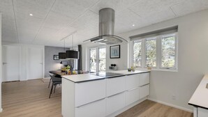 Una cocina moderna con una isla central, ventanas amplias e iluminación empotrada en el techo.