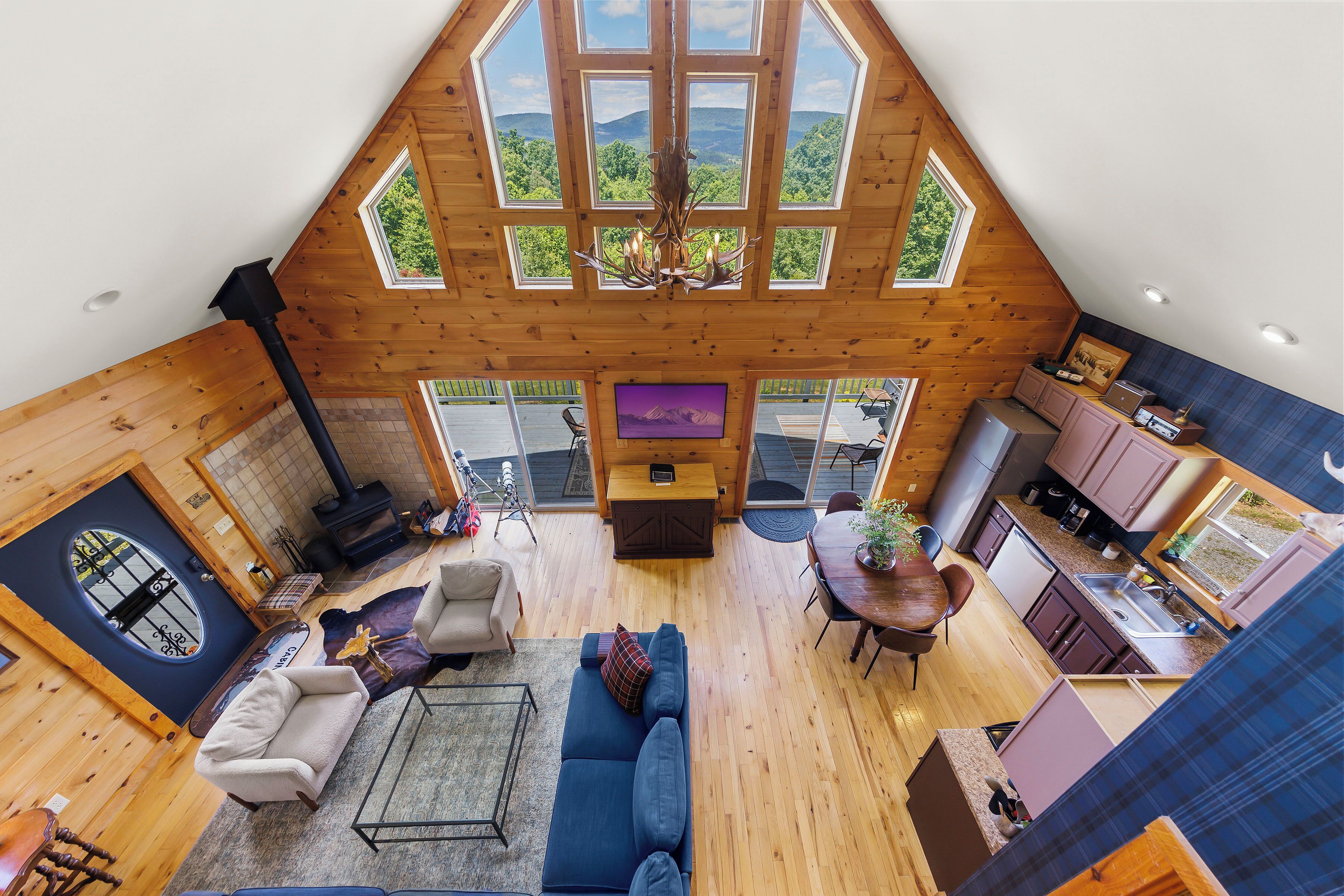 A high-ceilinged room with a fireplace, a sofa, a dining table, and a kitchen area.