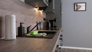 Una cocina moderna con encimera de madera, pileta de acero inoxidable y cafetera.