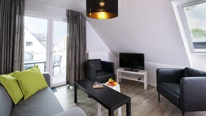 Una sala de estar moderna con un sofá, dos sillones, una mesita de centro y un televisor.