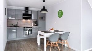 Una cocina moderna con armarios grises, una mesa de comedor blanca y dos sillas grises.