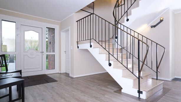 Una habitación amplia con una escalera en espiral, suelo de madera y un comedor con mesa y sillas.
