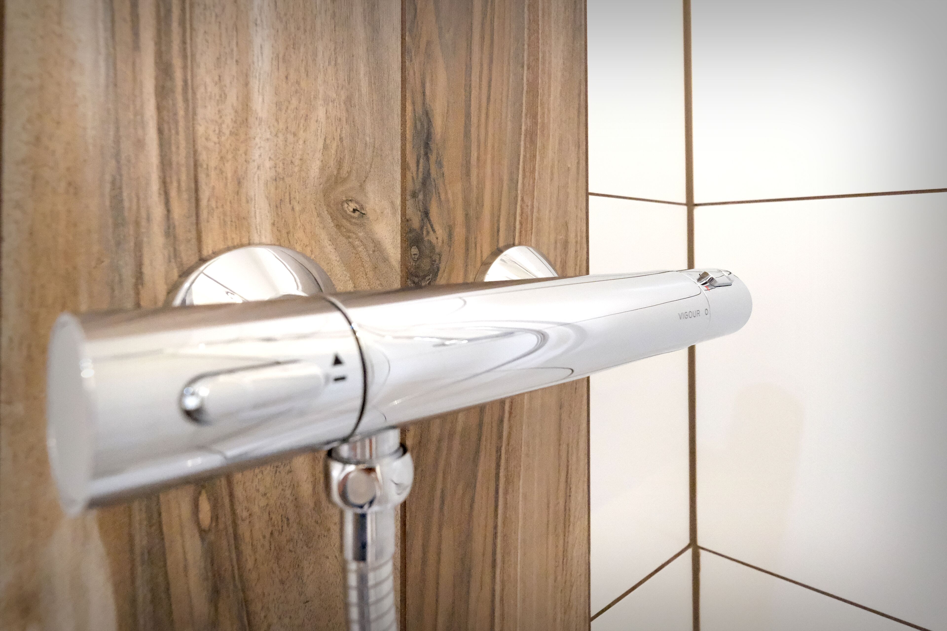 A modern bathroom with a wooden wall and a white tiled floor.
