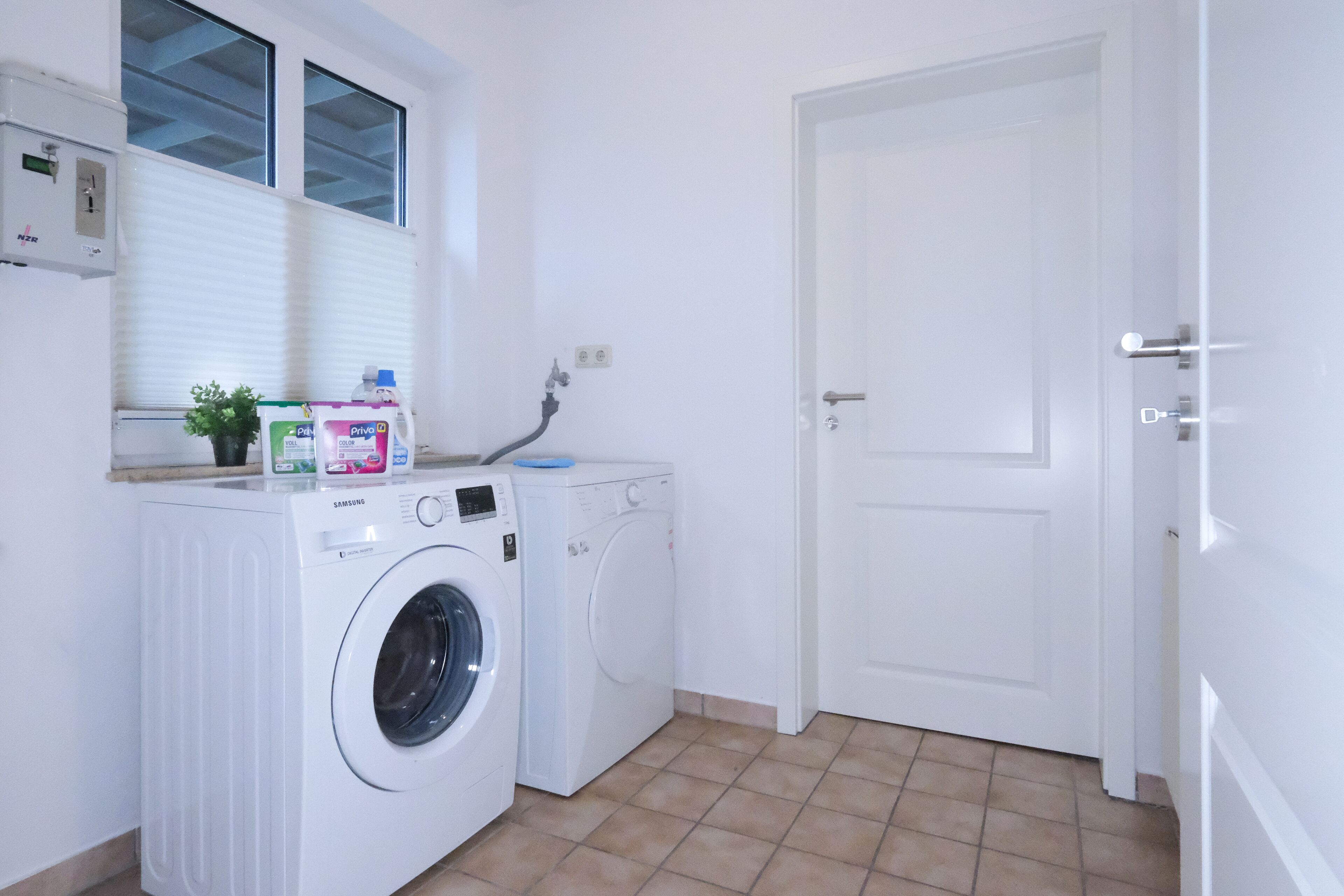A laundry area with two washing machines, a window, and a door.