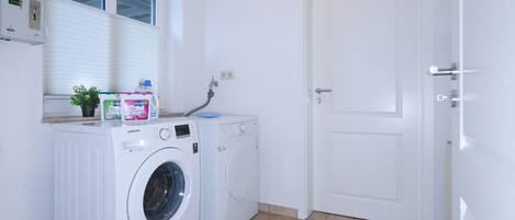 A laundry area with two washing machines, a window, and a door.