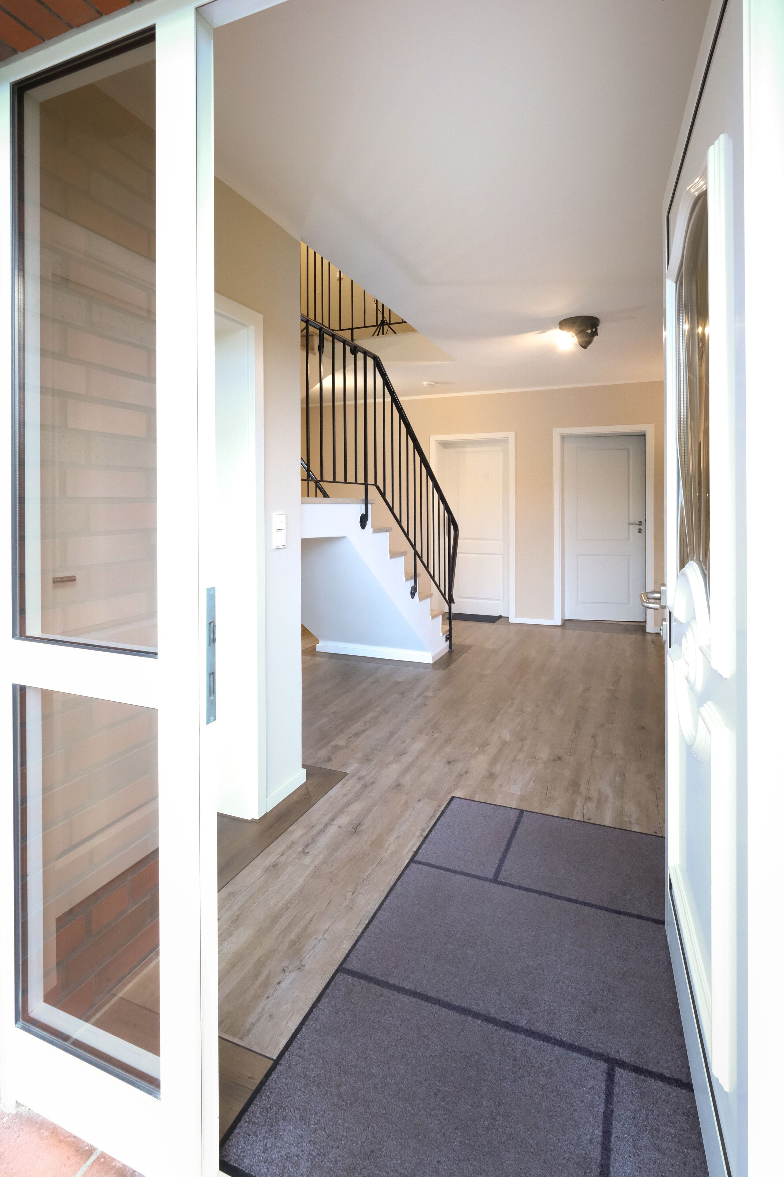 Un interno moderno con una scala, una porta e un tappetino.
