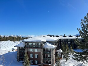 A multi-story hotel with a stone facade, large windows, and a snow-covered roof.